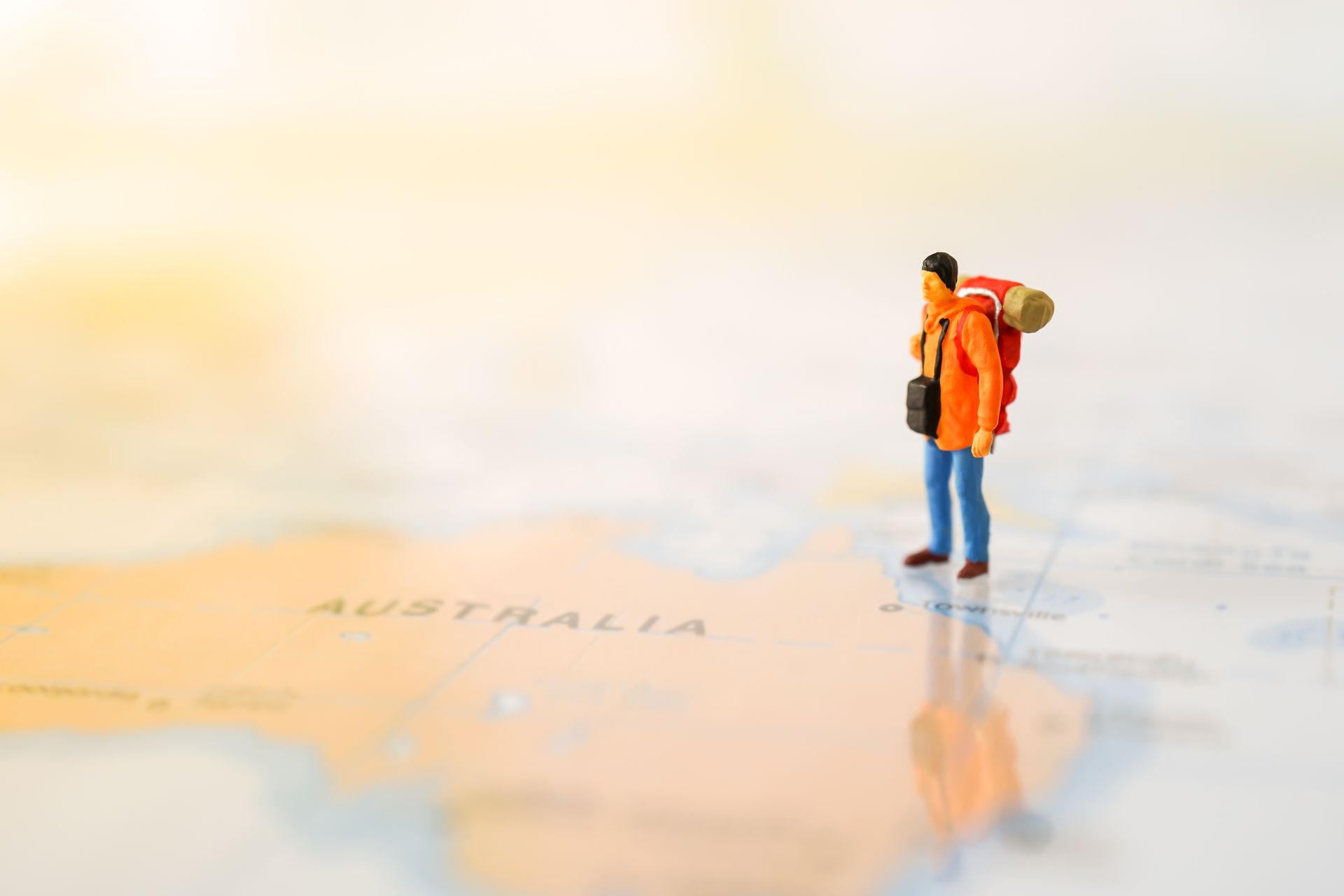 A miniature traveler man with a backpack carrying on his back