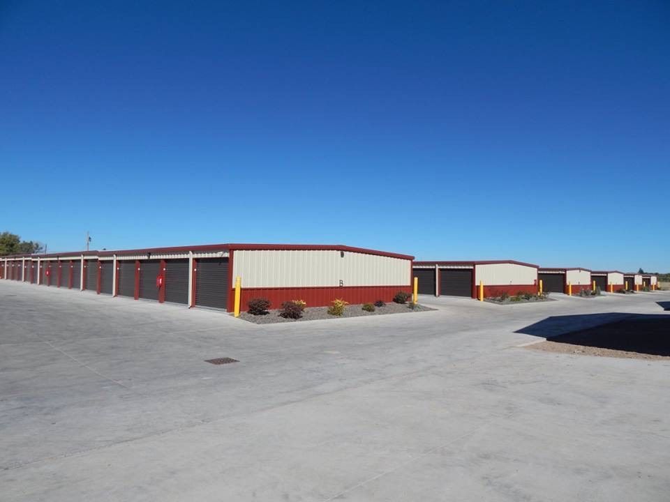 Row of red-and-white storage buildings on a wide paved lot under a clear blue sky