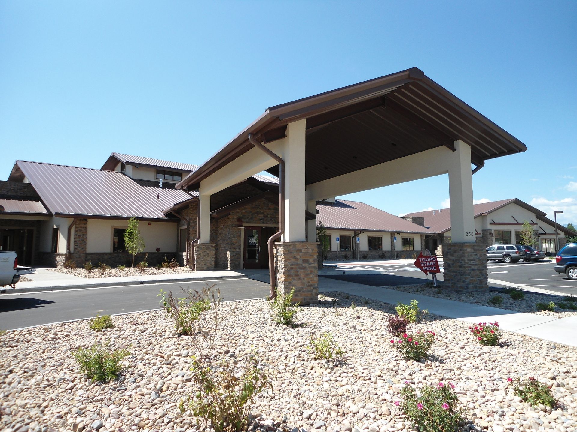 Covered driveway entrance at a residential complex with stone pillars and white gravel landscaping