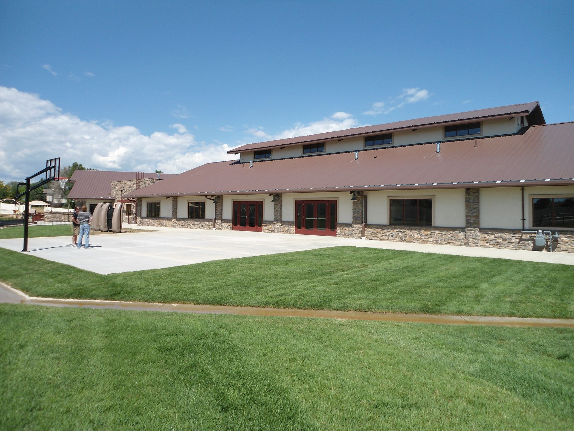 Low building with brown roof beside a green lawn under a blue sky