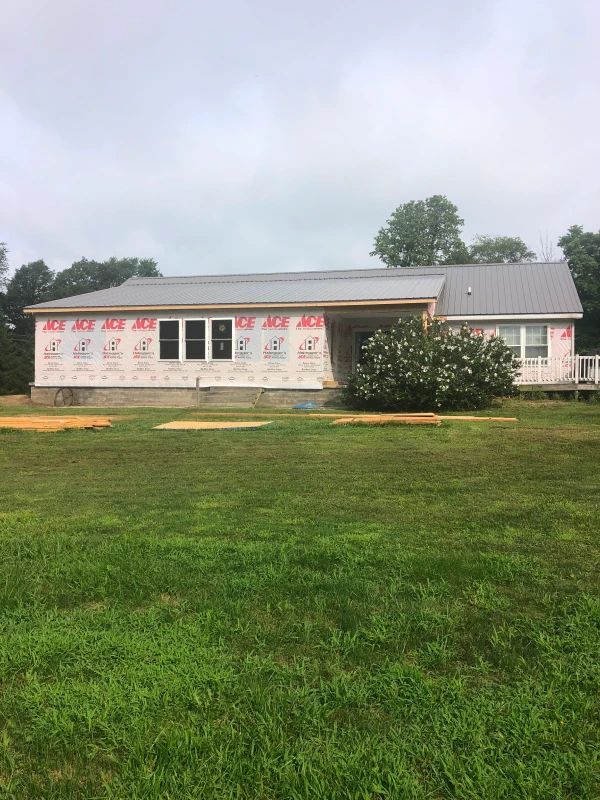 Small white building with red lettering, set on a grassy lawn under an overcast sky.