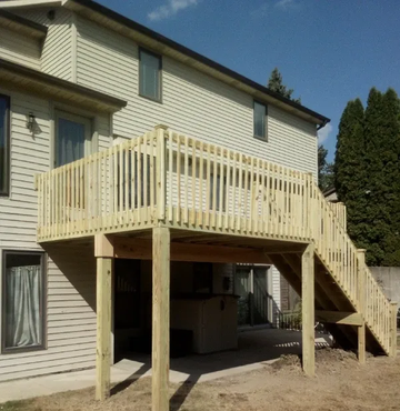 Outdoor deck with a dining set and grill under a covered patio, overlooking a backyard.
