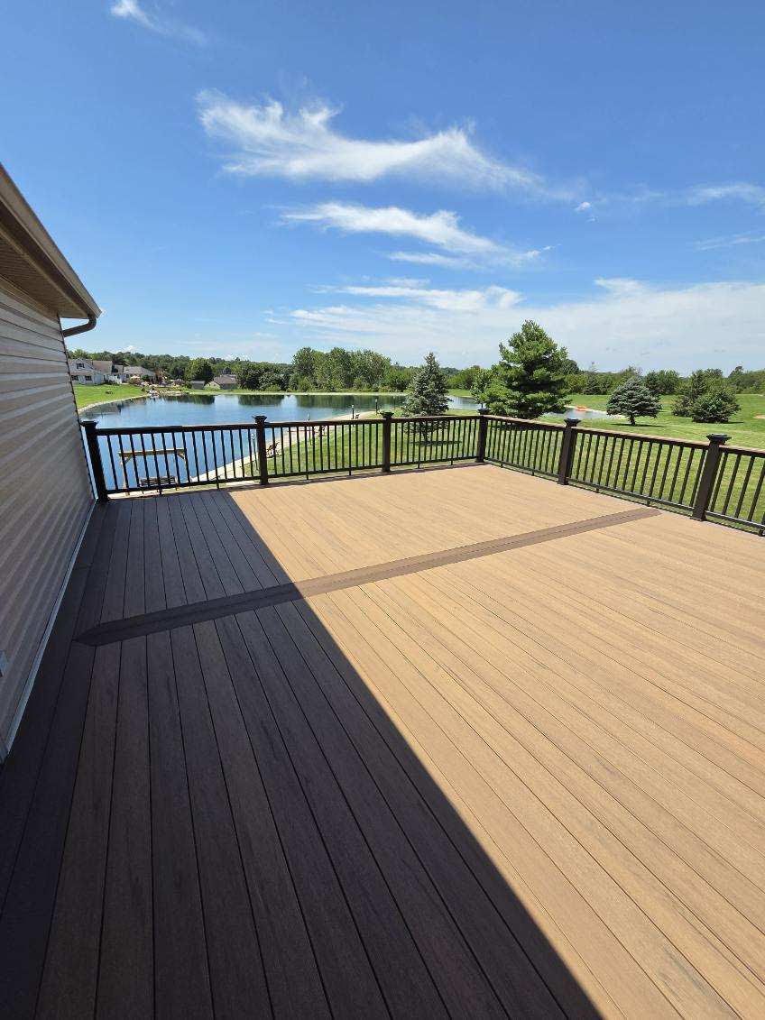 Spacious wooden deck overlooking a lake and green landscape under a blue sky