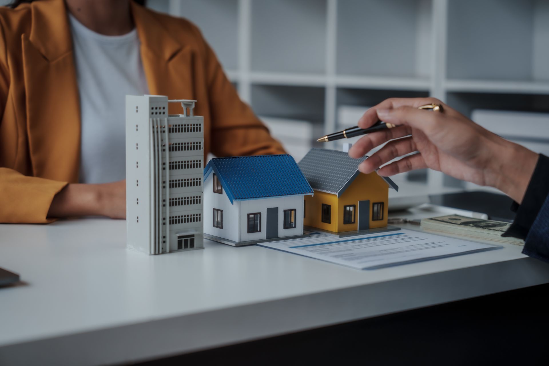 Person pointing pen at property models on table with another person.