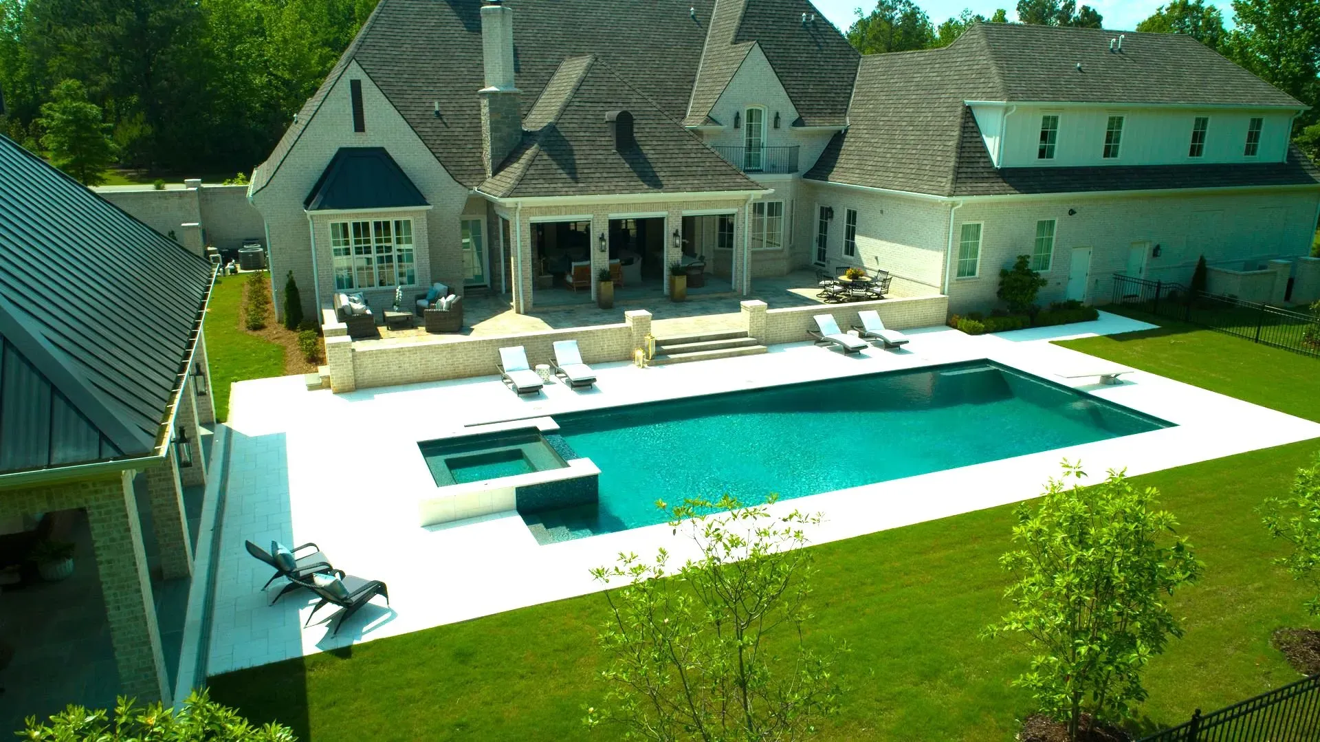 Luxurious home with a pool and lounge chairs; sunny outdoor setting.