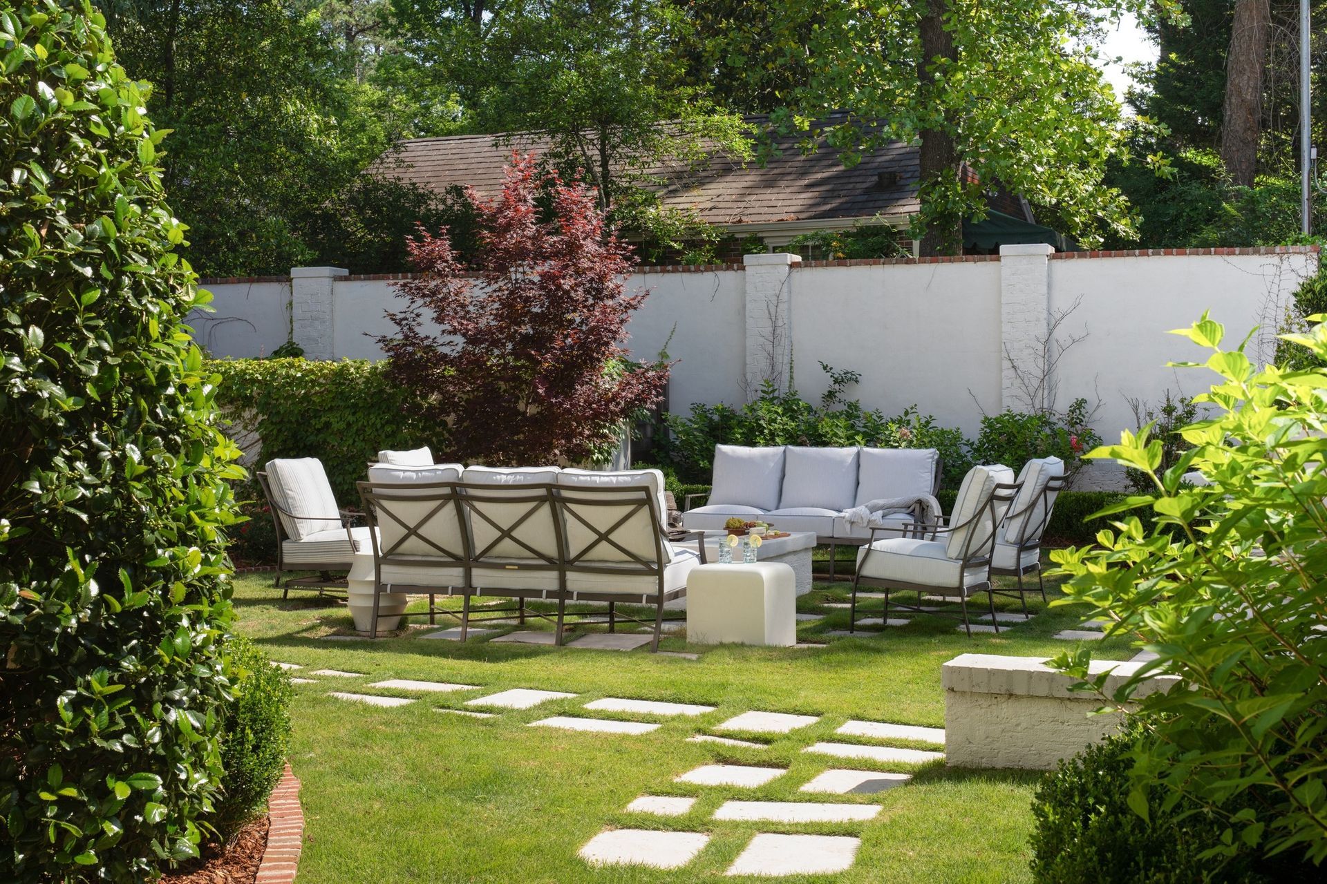 Wooden chair with white cushions, table with decor, overlooking water.