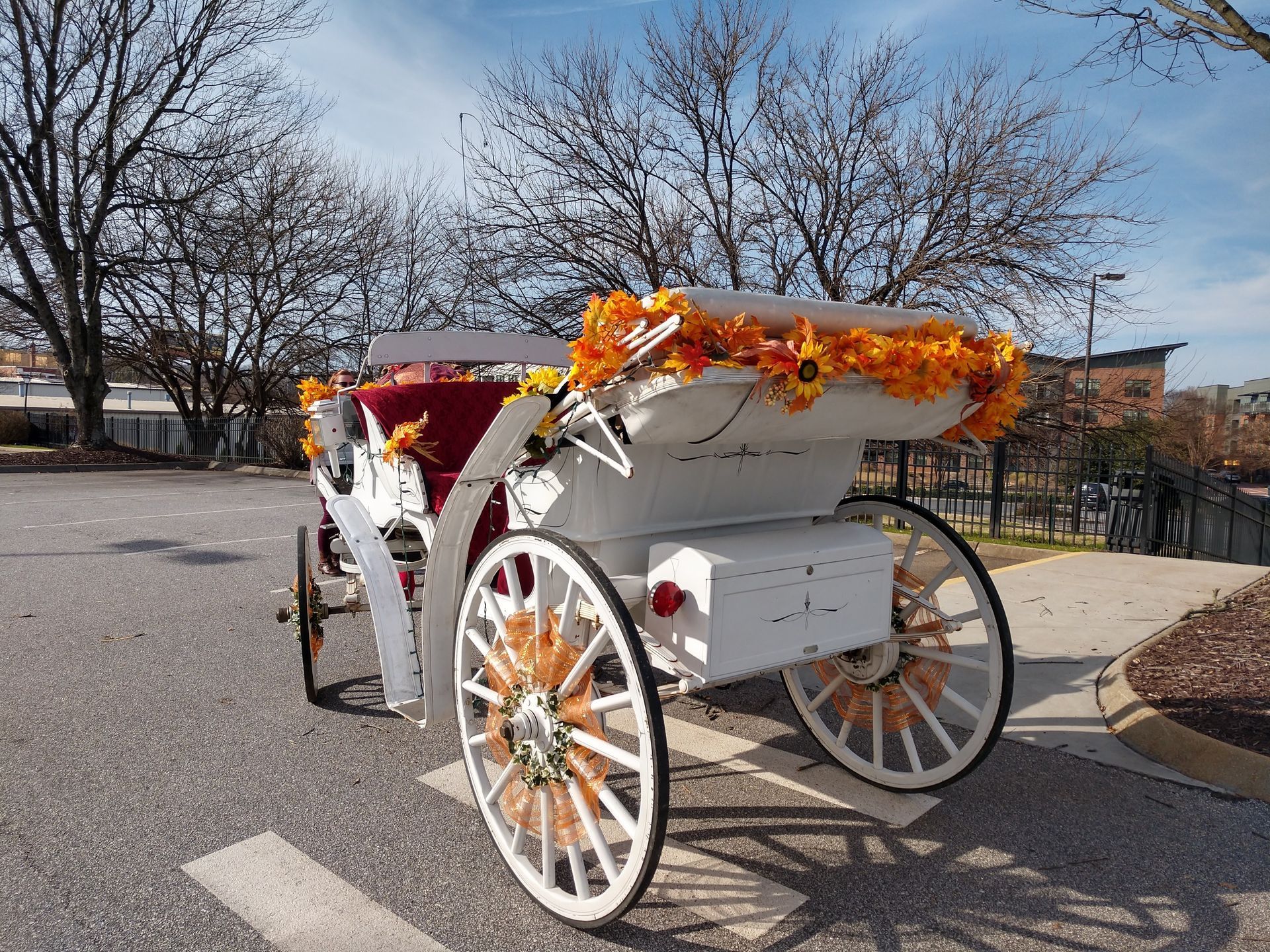 Decorated white horse carriage with orange flowers parked on a sunny street
