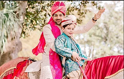 Man and child in bright traditional attire riding a decorated horse outdoors, both smiling