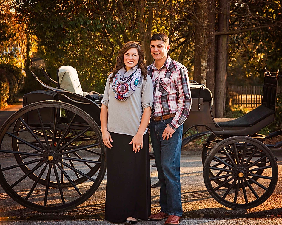 Two people standing beside a horse-drawn carriage in an autumn park
