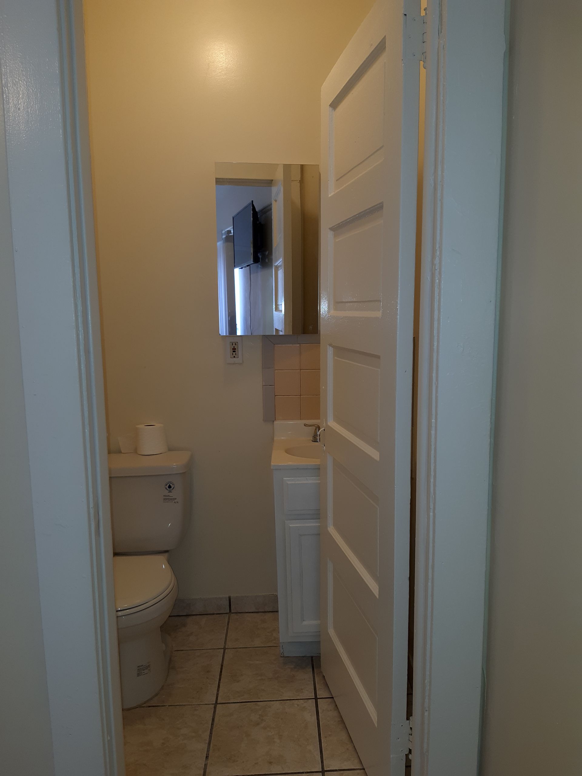 A bathroom with a toilet , sink and mirror.