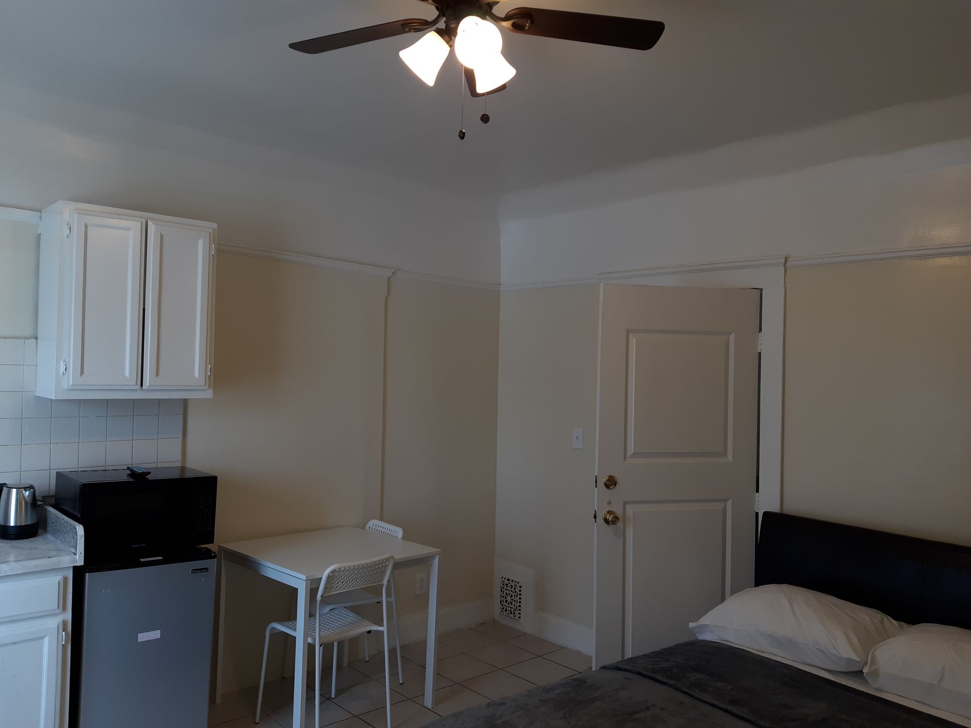 A bedroom with a table and chairs and a ceiling fan