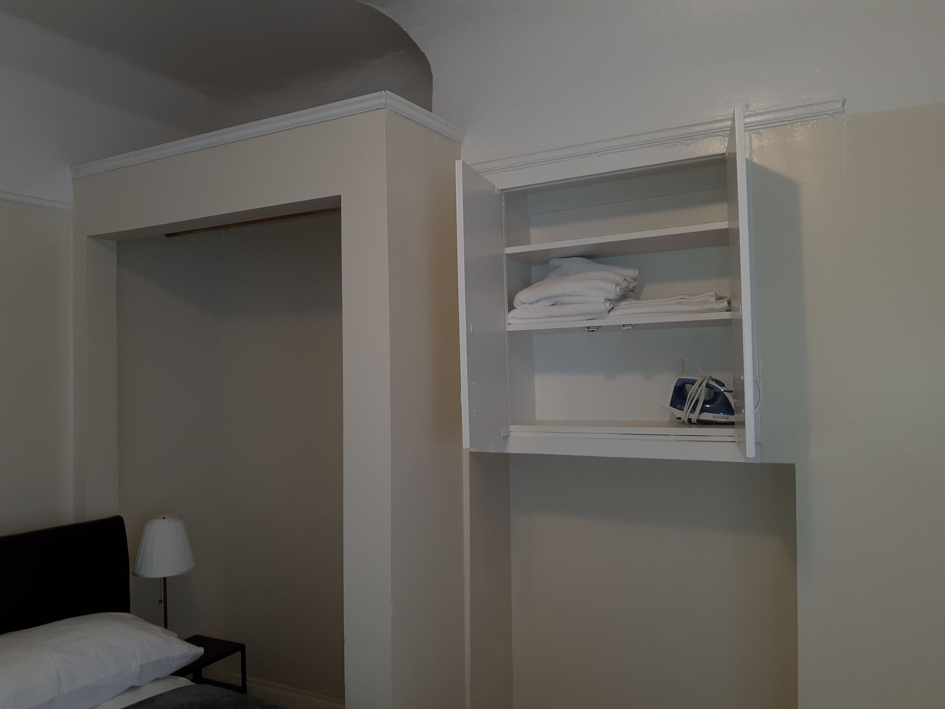 A bedroom with a bed , a lamp , and a closet.