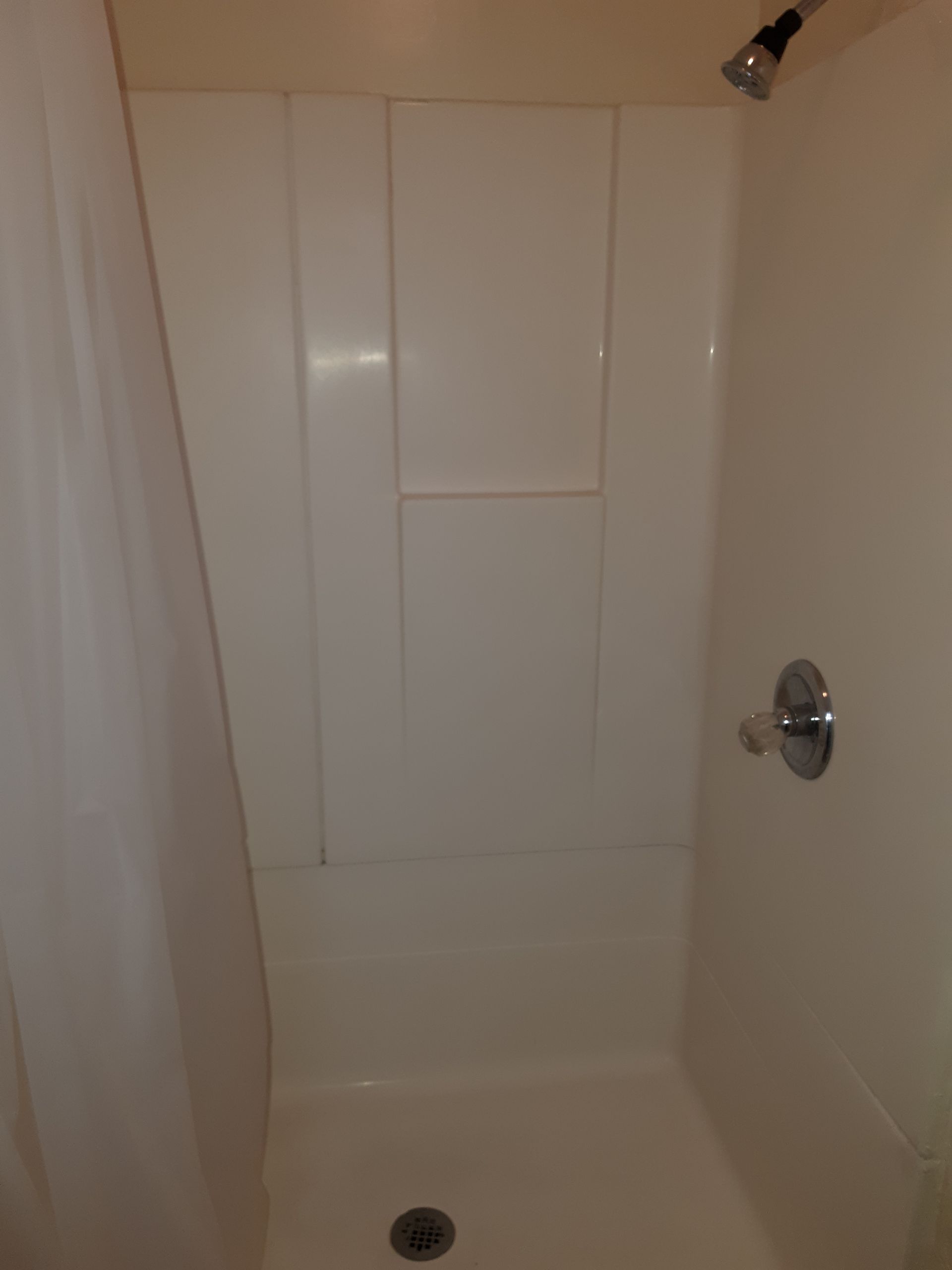 A shower stall with a shower head and a shower curtain in a bathroom.