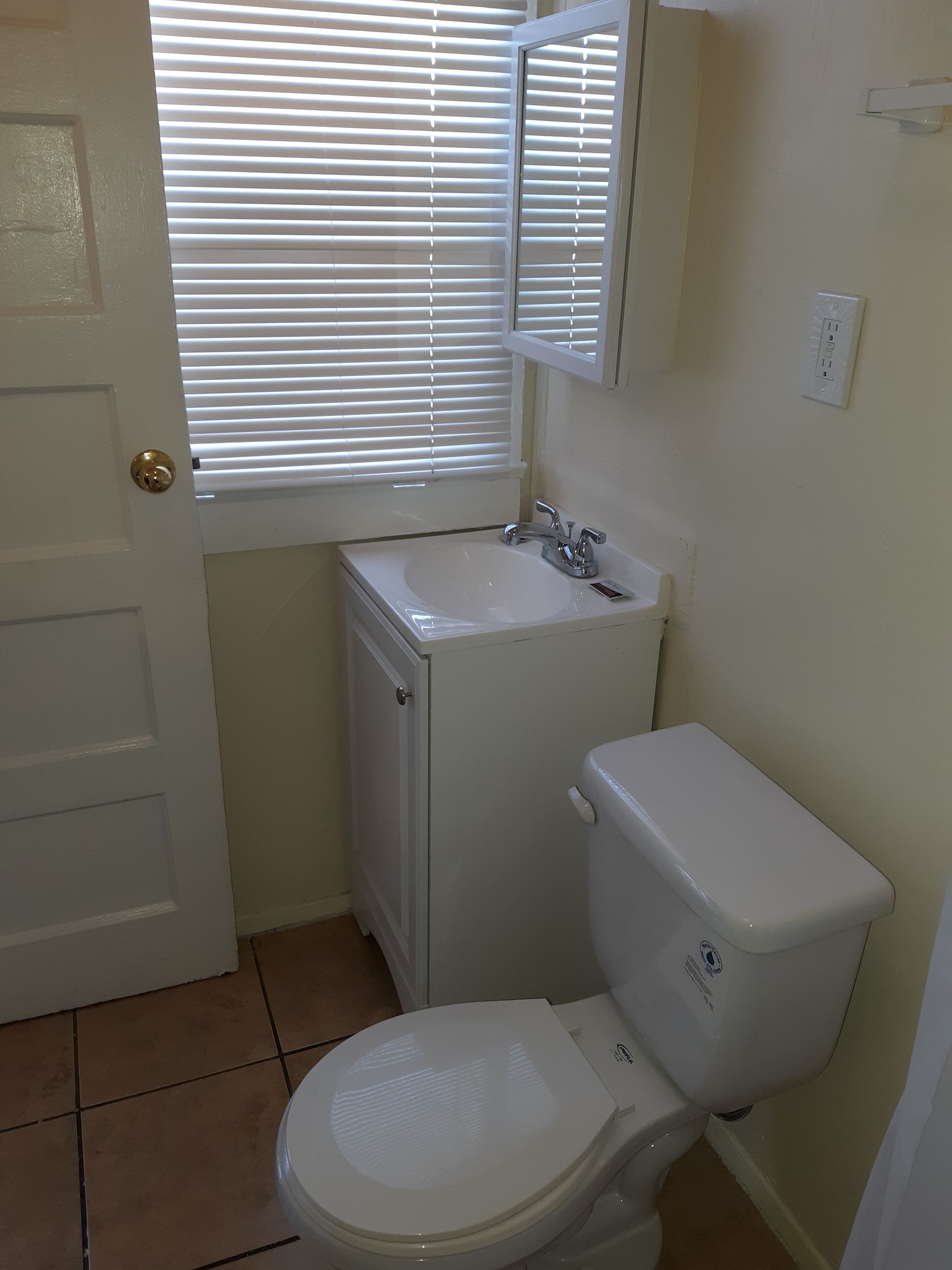 A bathroom with a toilet a sink and a window