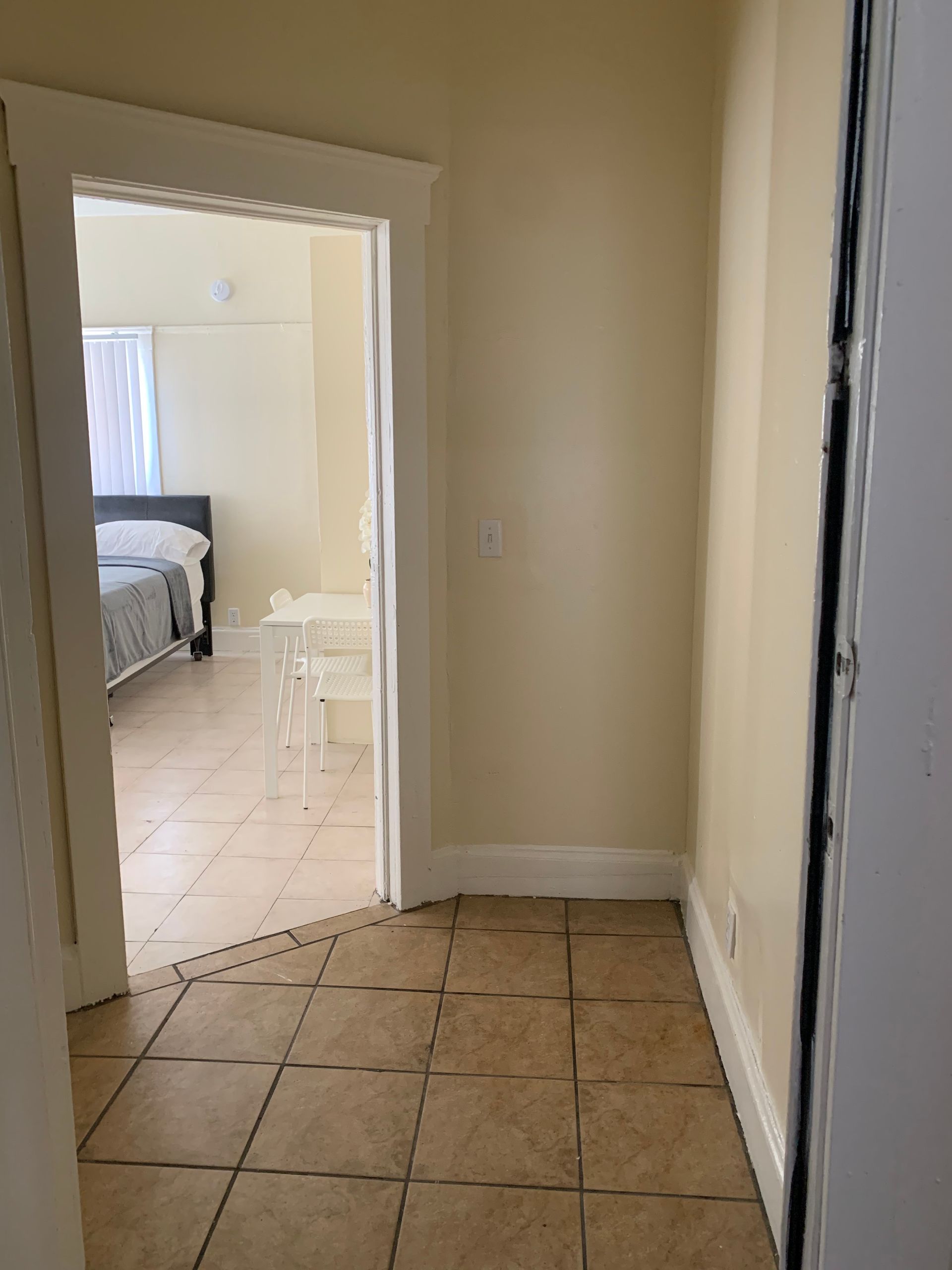 A hallway leading to a bedroom with a tiled floor.