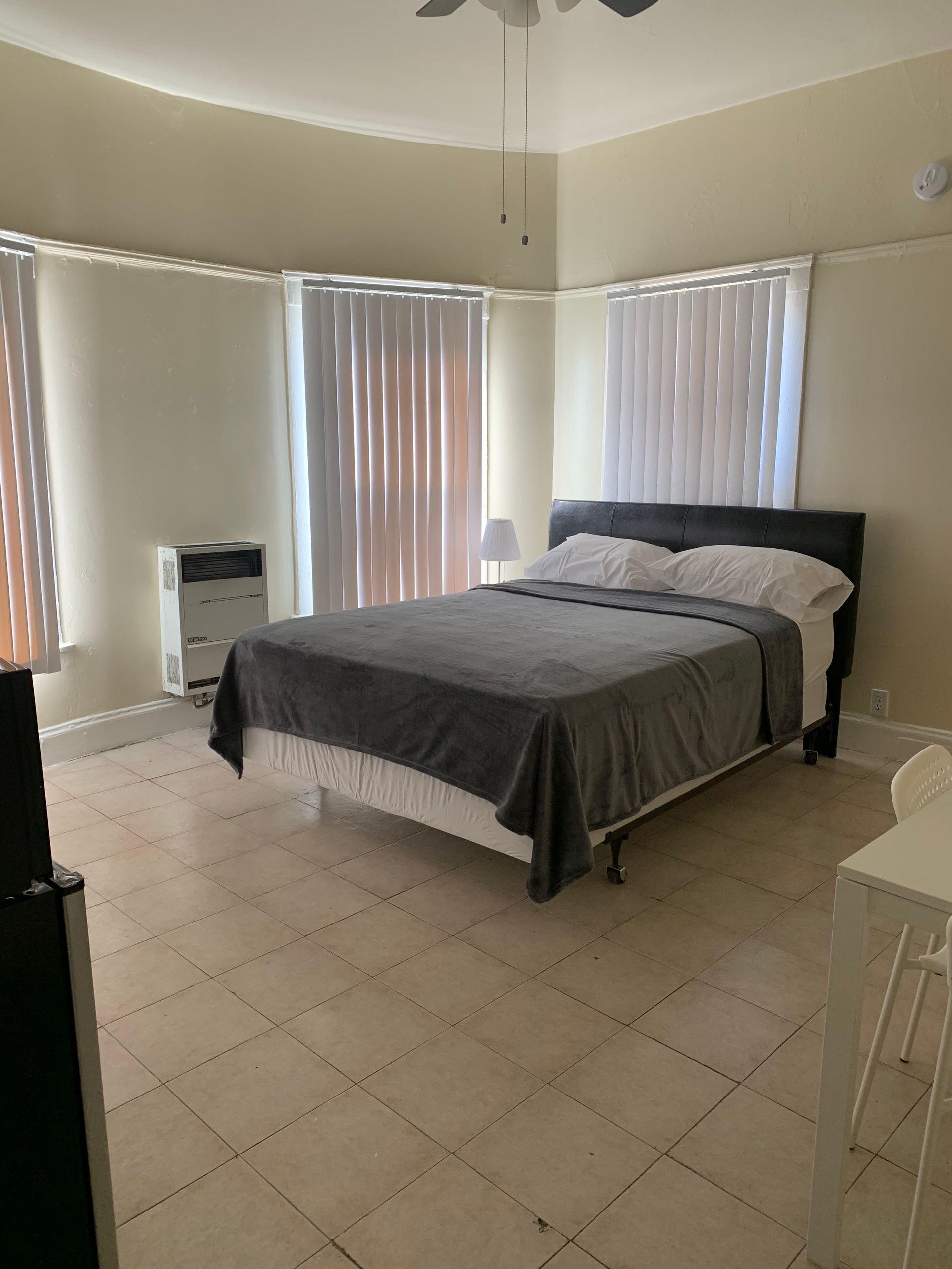 A bedroom with a large bed and a ceiling fan