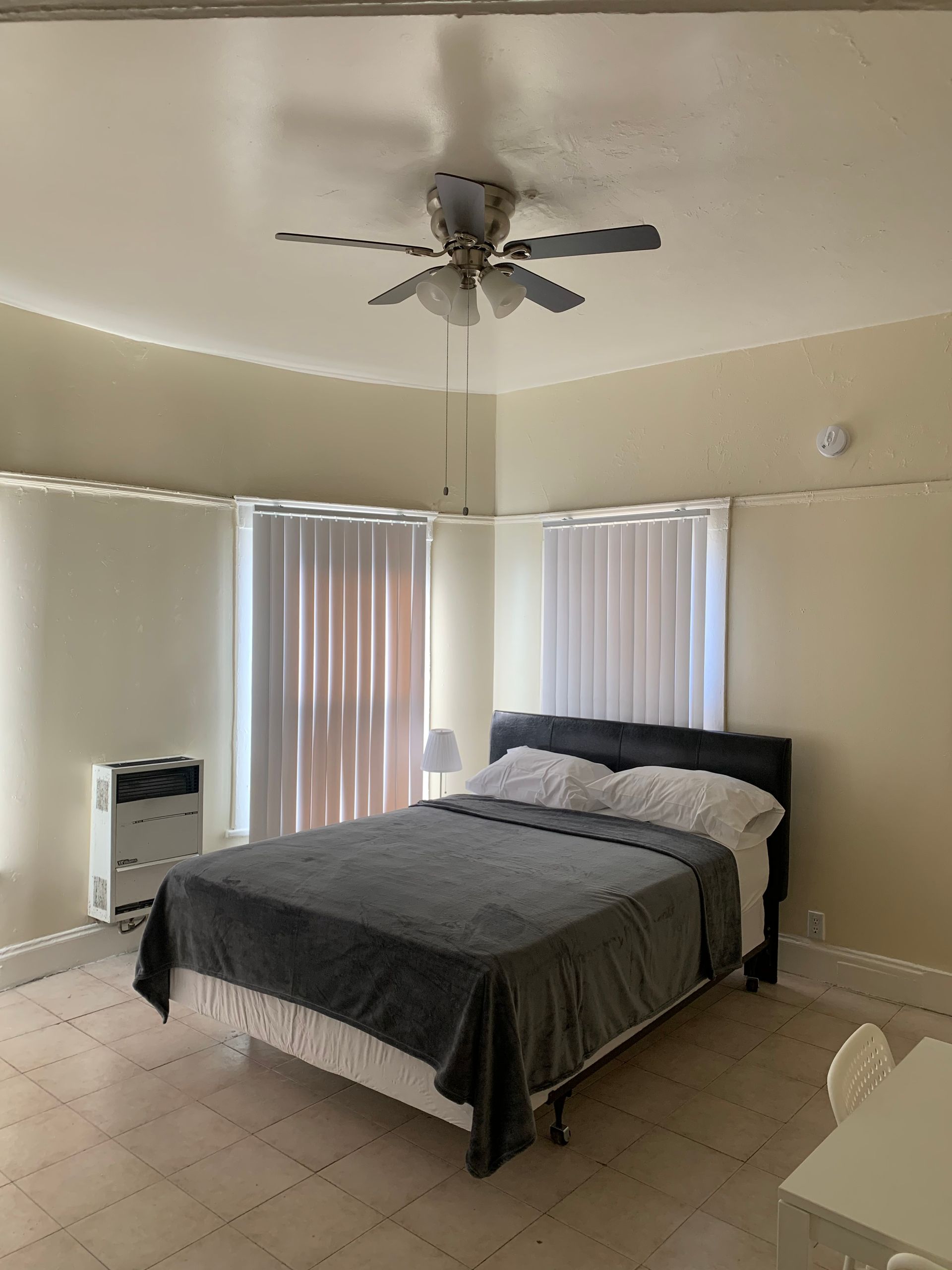 A bedroom with a bed and a ceiling fan