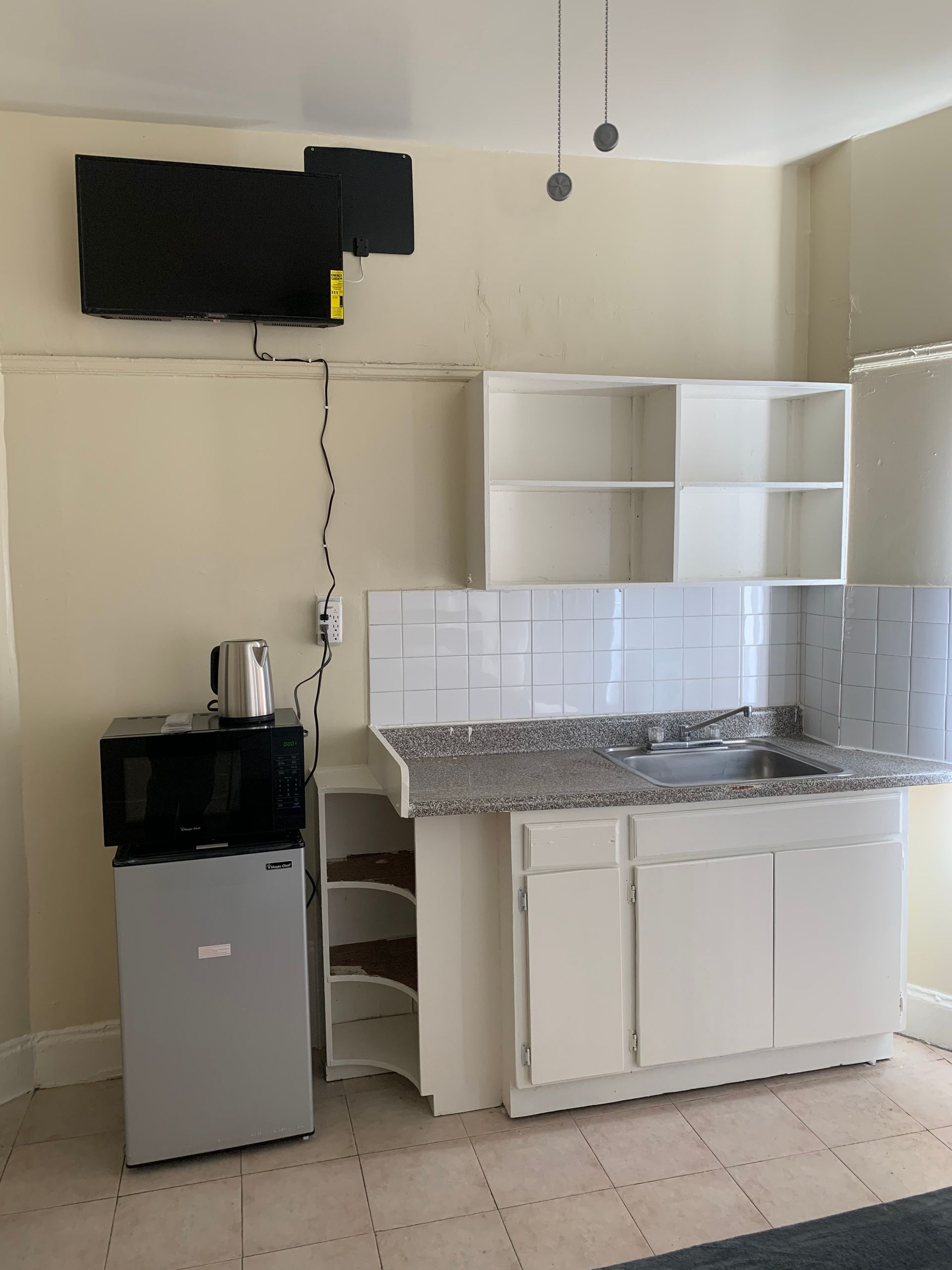 A kitchen with white cabinets and a small refrigerator