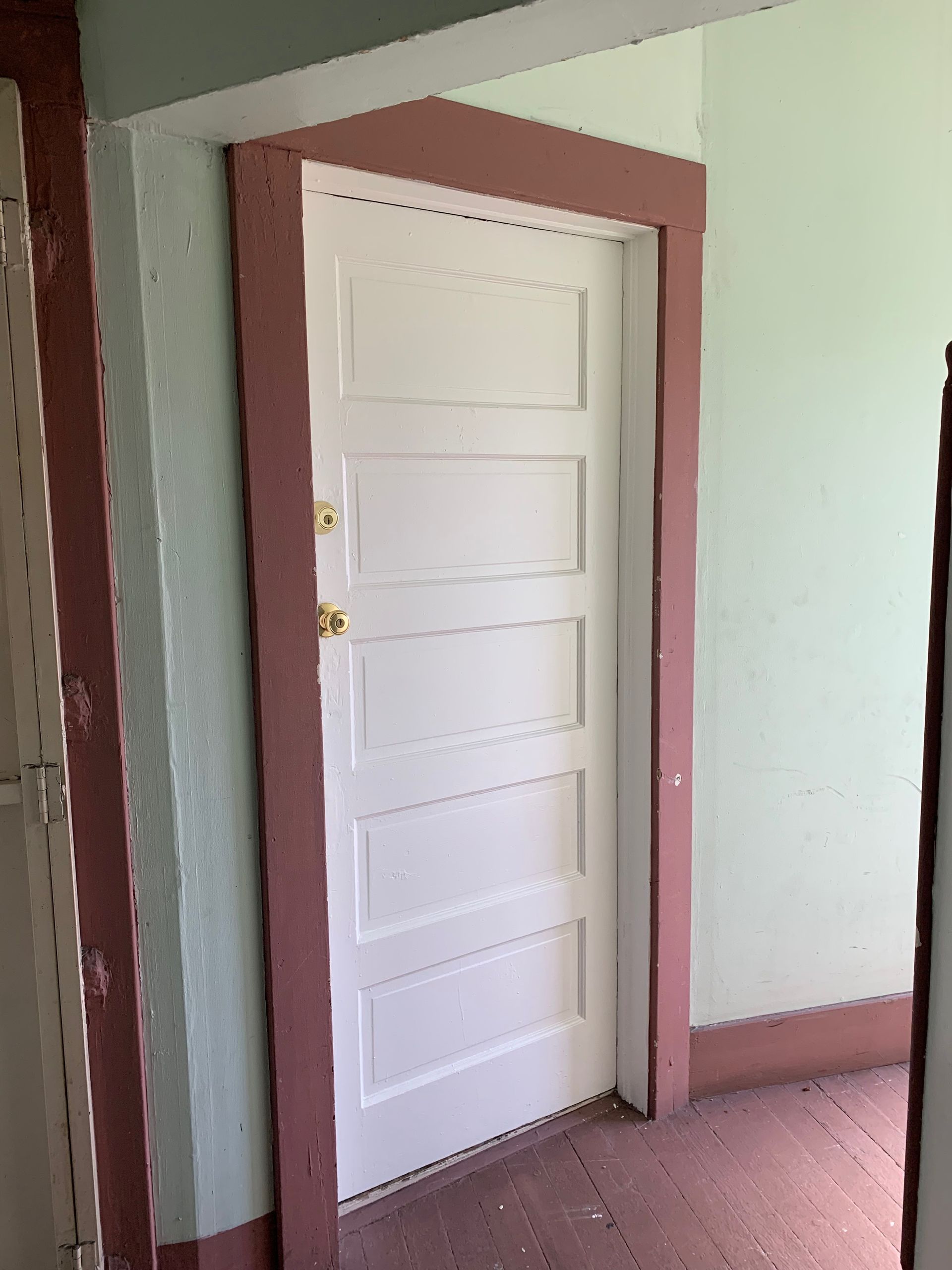 A white door with a pink trim is in a hallway.