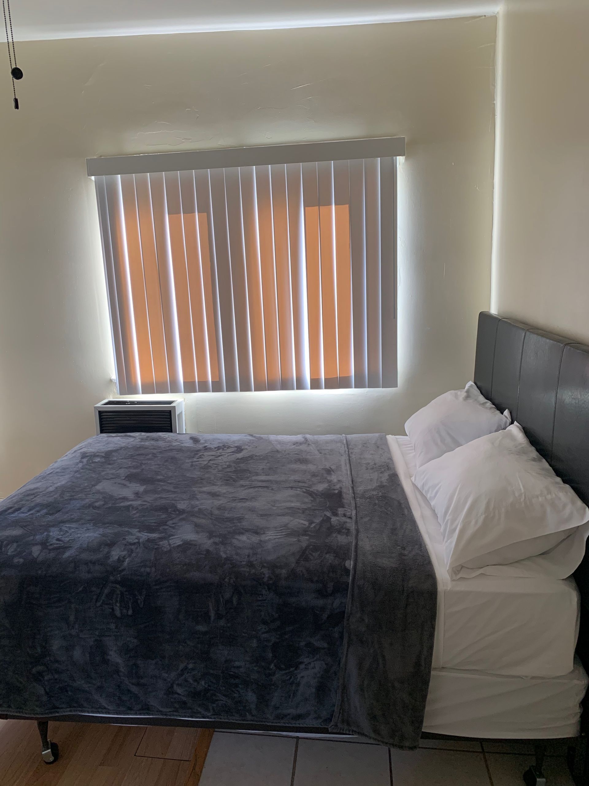 A bedroom with a bed and a window with blinds