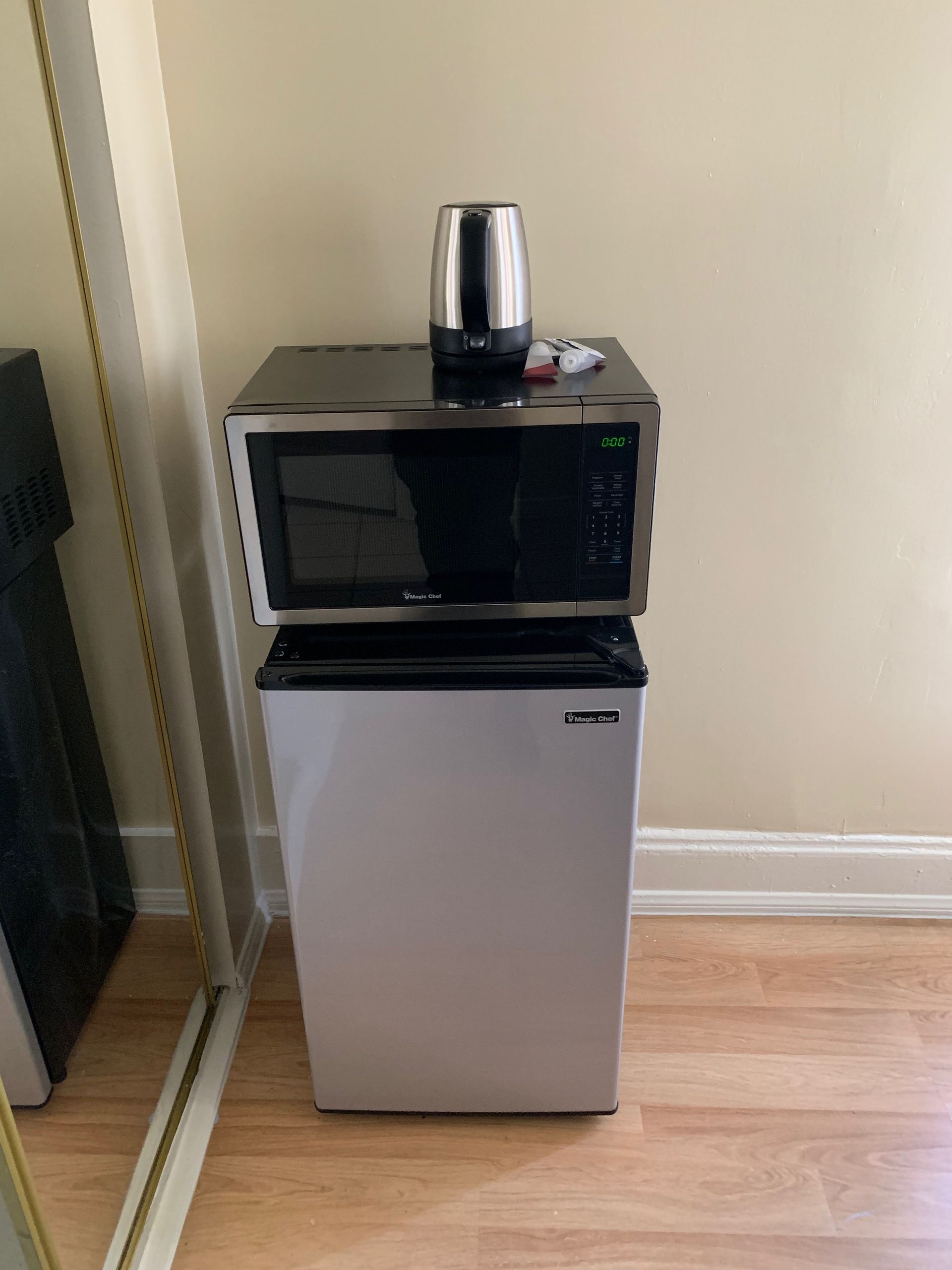 A small refrigerator with a microwave on top of it.