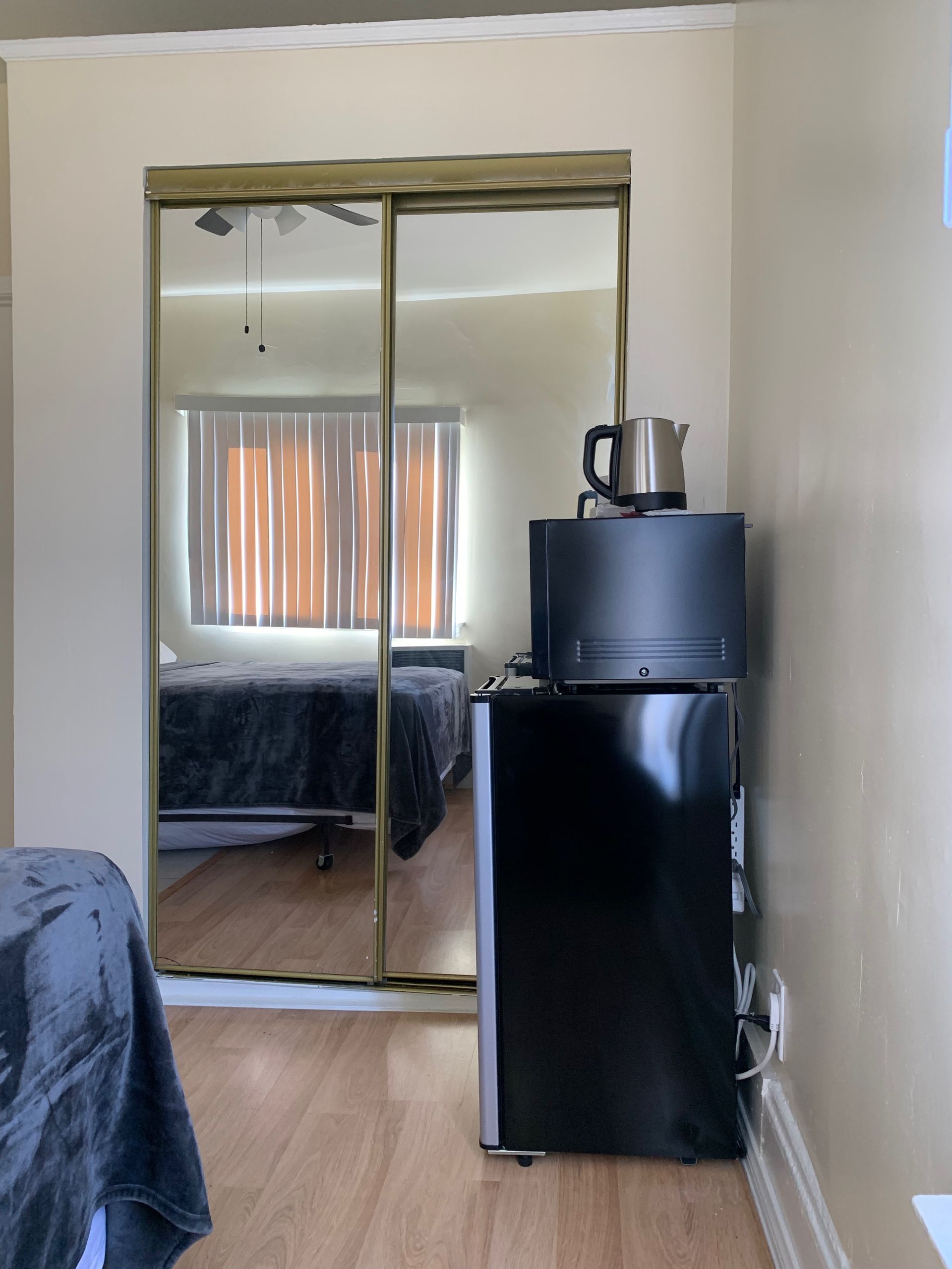 A bedroom with sliding glass doors and a black refrigerator