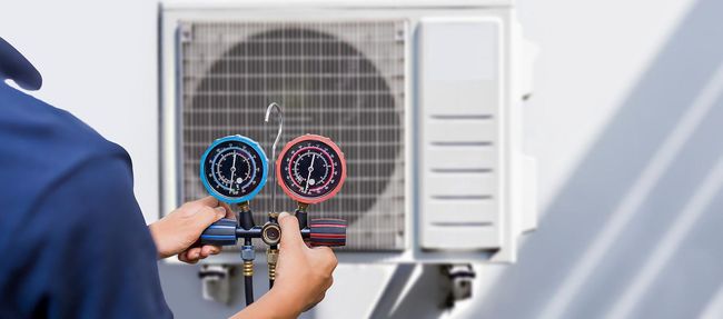 Technician adjusting gauges on an outdoor air conditioner unit