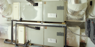 Two stacked HVAC units with wrapped ductwork in a utility room