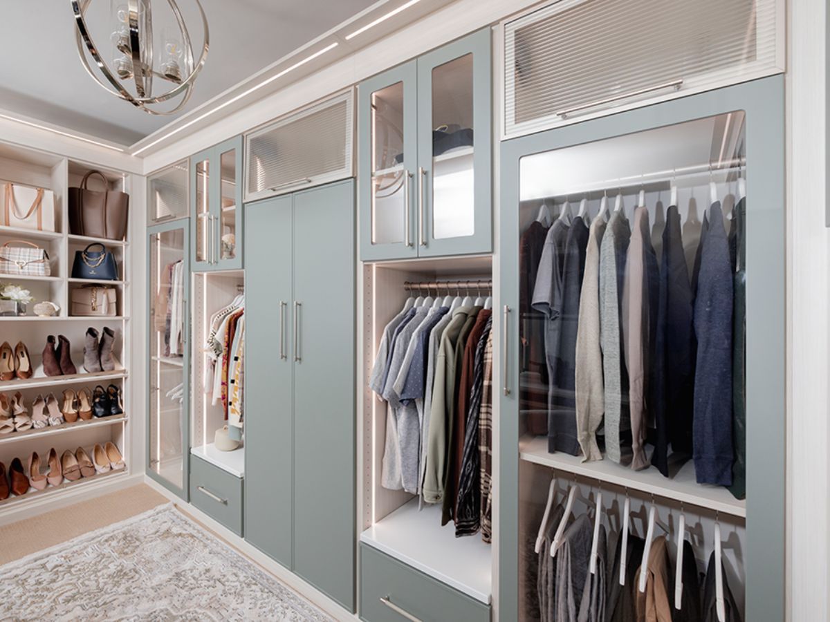 Elegant walk-in closet with mirrored cabinets, blue doors, shoe shelves, and neatly hung clothes