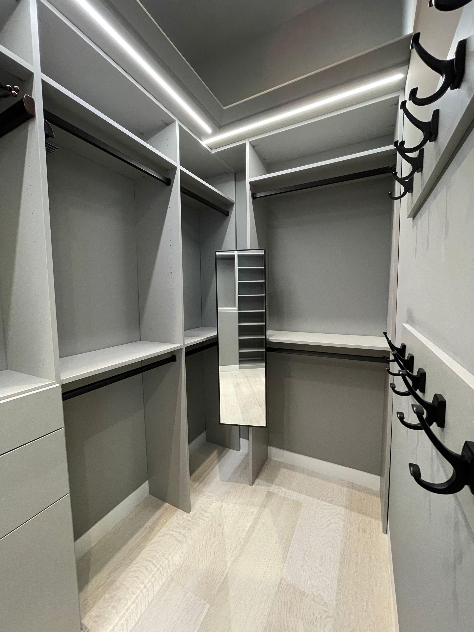 A walk in closet with lots of shelves and a mirror.