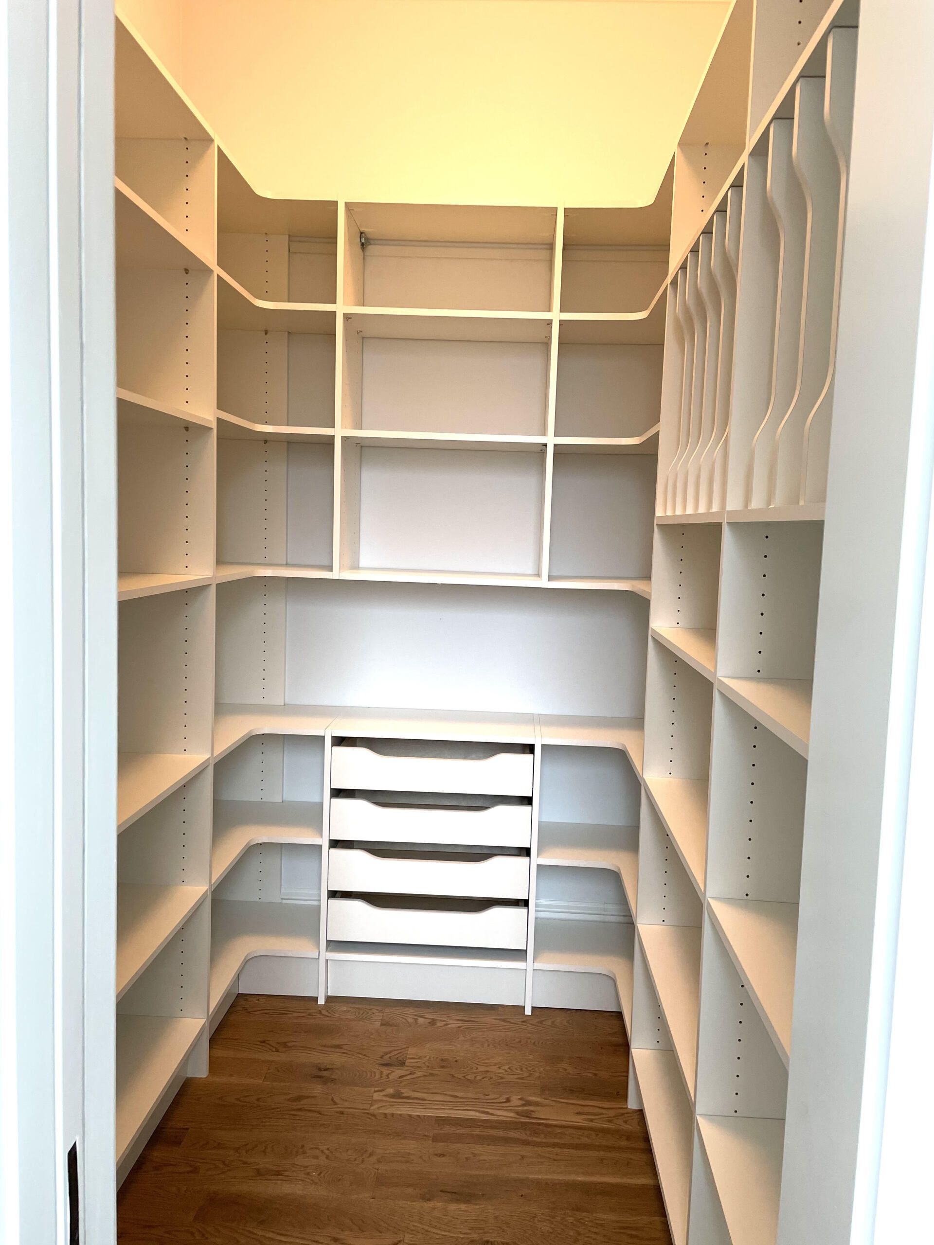 A walk in closet with lots of shelves and drawers