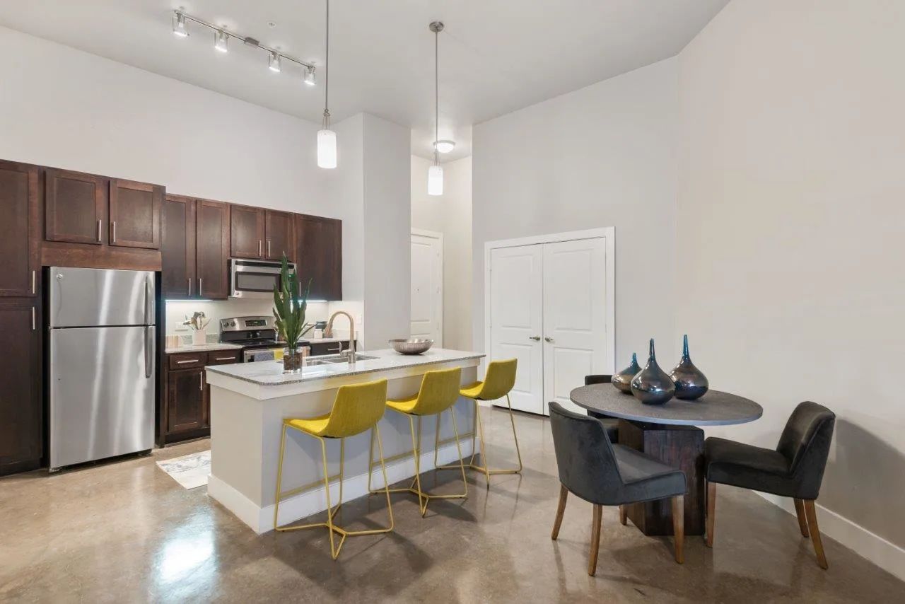 A kitchen with stainless steel appliances , a table and chairs.