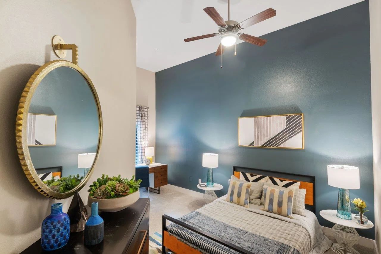 A bedroom with a bed , dresser , mirror and ceiling fan.