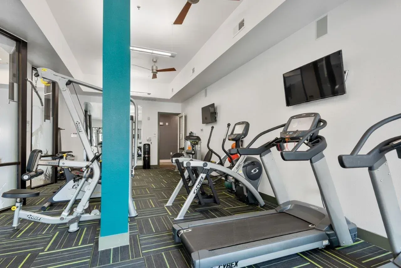 A gym with treadmills , exercise bikes , and a television on the wall.