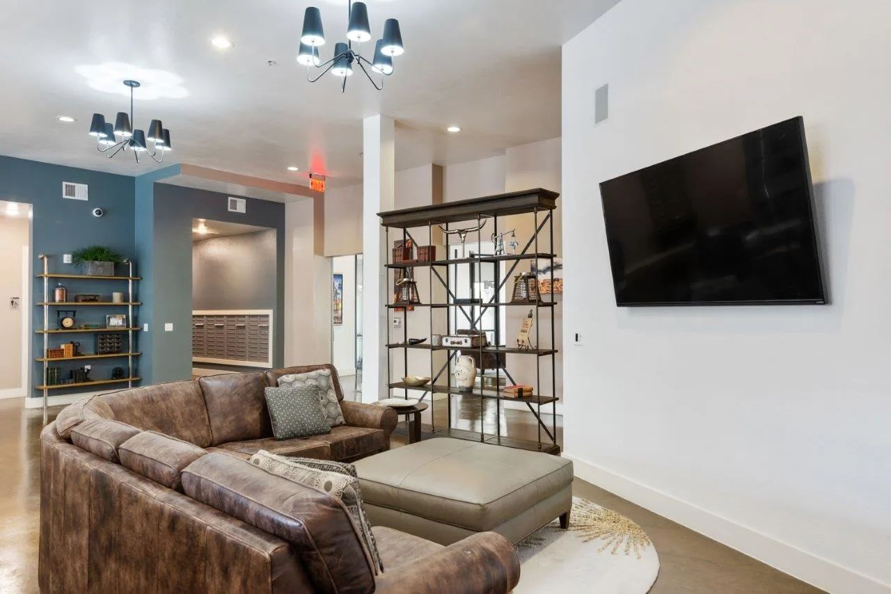 A living room with a couch and a flat screen tv on the wall.