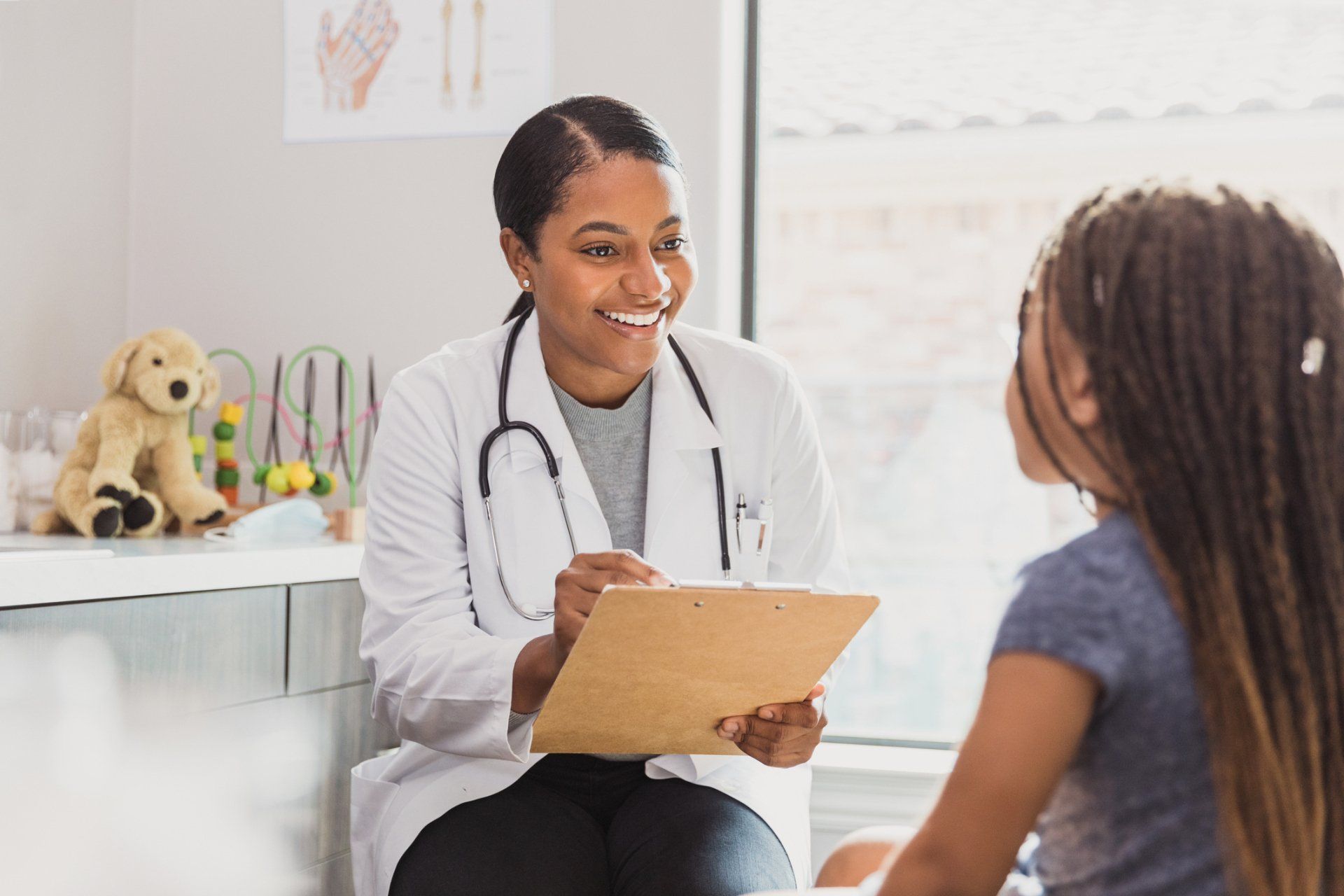 Mid adult female doctor listens to the preschool age patient