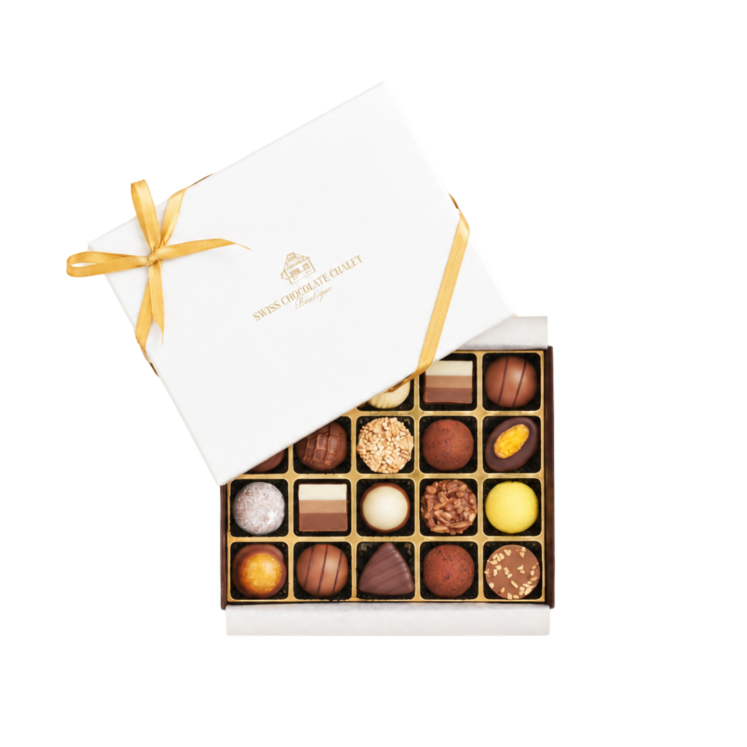 Offene weiße Geschenkbox mit goldenem Band, die eine Auswahl an Pralinen in einer ordentlichen Einlage zeigt