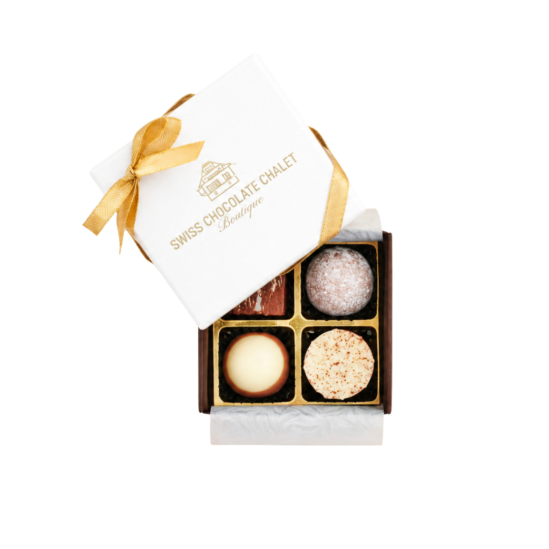 Geschenkbox mit vier verschiedenen Süßigkeiten, goldenem Band und weißem Deckel vor weißem Hintergrund