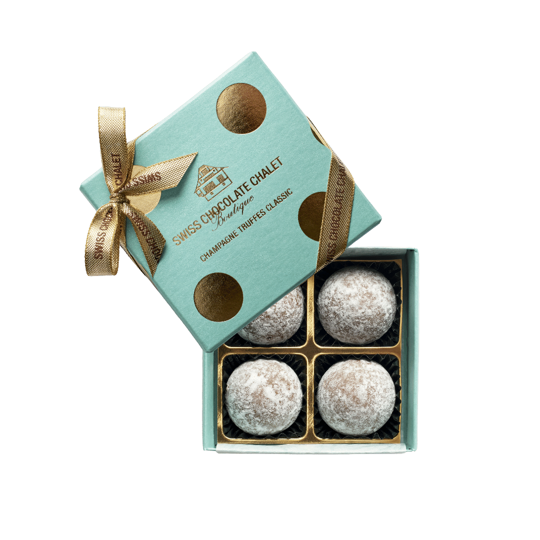 Offene Geschenkbox mit vier silbernen Pralinen und einem goldenen Band auf einem mintgrünen Deckel