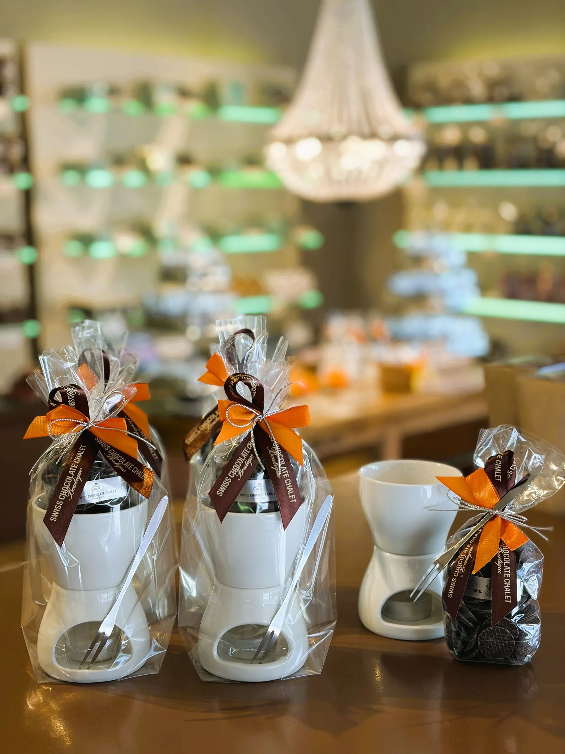 Die Auslage eines Schokoladengeschäfts ist gefüllt mit verschiedenen Pralinen auf Holzregalen unter warmem Licht.