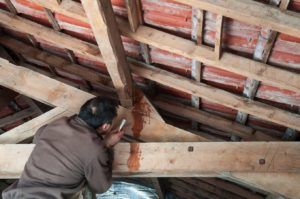 A man is working on a wooden structure under a roof.