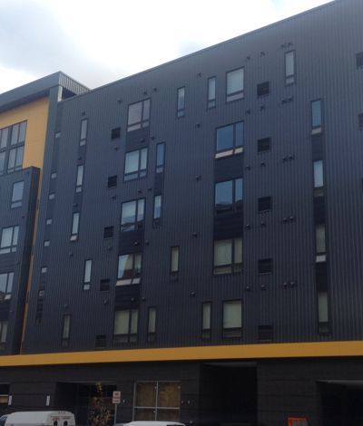Dark gray building with varied window shapes and yellow accents.