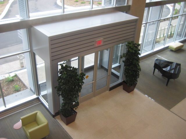 Entryway with glass doors and windows, plants, and a piano inside a building.