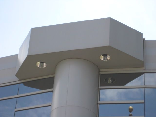 White building with octagonal structure supported by a cylindrical column and glass windows.