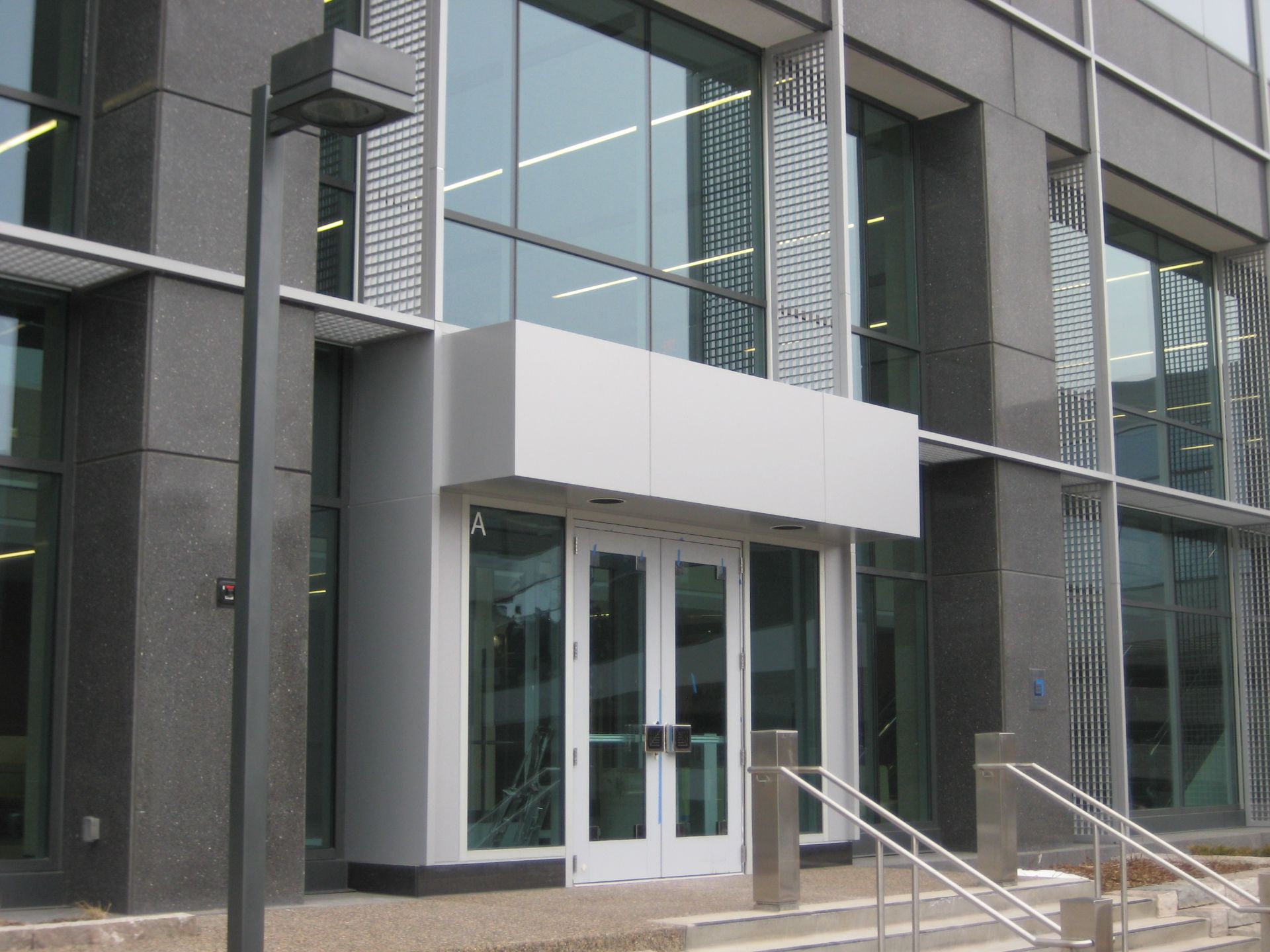 Building entrance with glass doors, silver trim, and dark gray stone facade.