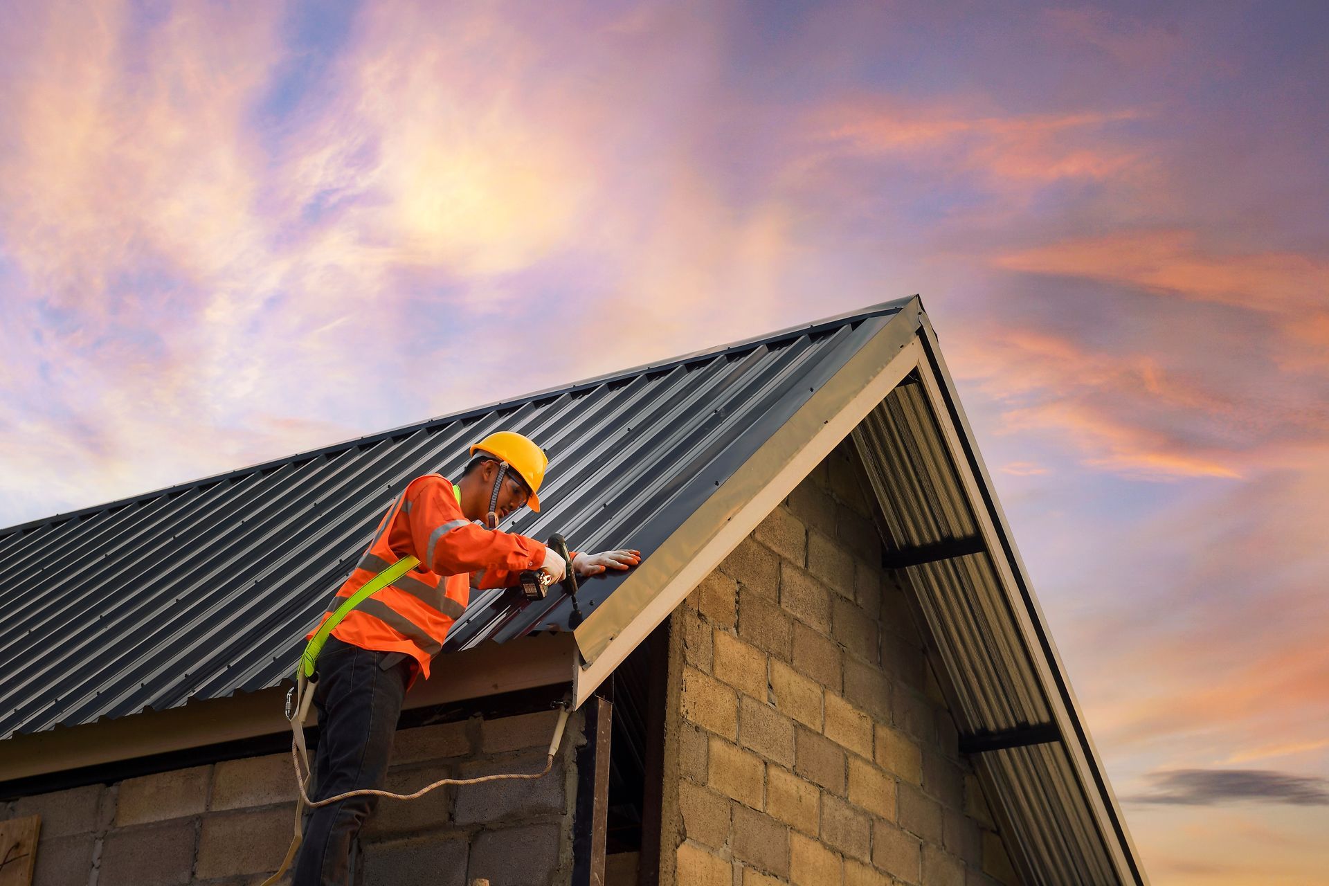Construction worker installing metal sheets on a roof.