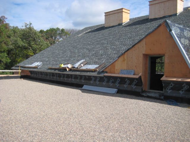 Roof construction: Asphalt shingles, wooden frame, gravel surface. Sunny outdoor setting.