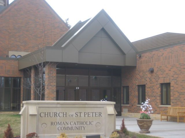 Church of St. Peter, Roman Catholic Community sign in front of a brick building entrance.