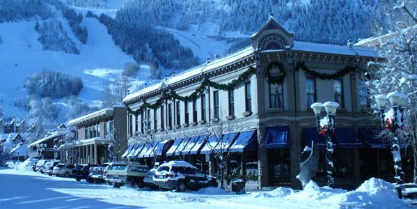 A city street covered in snow with a large building in the background.