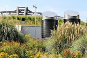 A building with a green roof is surrounded by tall grass and flowers.